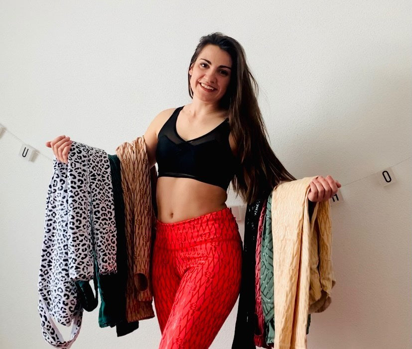 Female pole dancer posing and holding up her sticky leggings collection featuring Super Fly Honey's Sticky Fishnet Leggings, Sticky Leopard Leggings, and Sticky Geometric Leggings